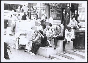 Group of people sitting outside by the Harvard Square T station