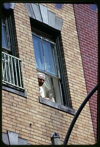Man viewing religious procession from window, North End, Boston