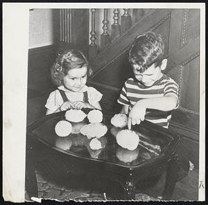 Hailstones-Peggy Jo, 3, and Rusty, 7, of Opheim, III., look at gigantic hailstones that fell during storm. Auto were dented and windshields broken. Largest stone shown measured sic inches the long way.