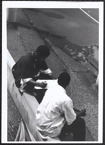 Junior Gabriel (on left) and another young man sitting and writing