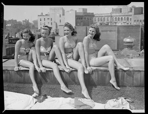 Girls in bikinis sunbathe on roof