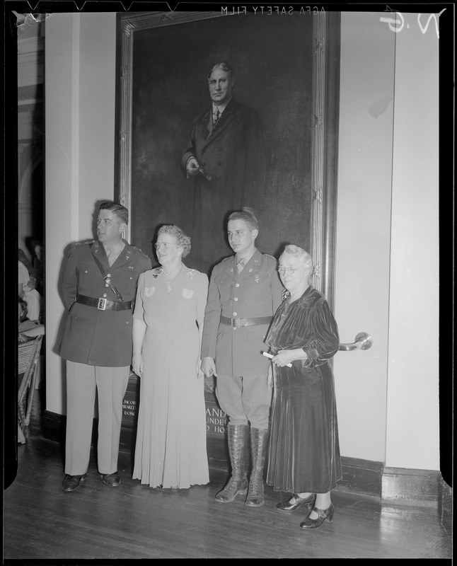 Group poses in front of portrait