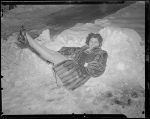 Woman in fur reclines in snow bank