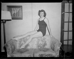 Girl poses in bathing suit on love seat
