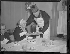 Cardinal Cushing serves dinner to elderly women