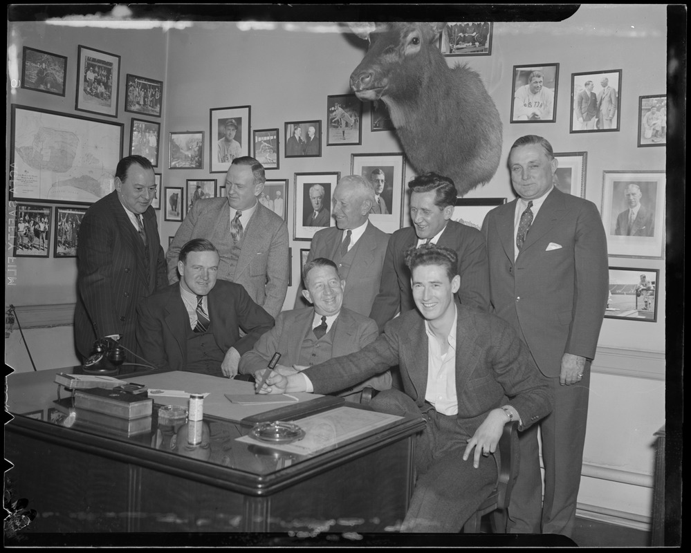 Ted Williams signs contract while Red Sox officials, including Cronin and Collins, look on