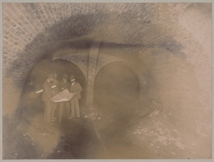 Men studying plans in split sewer