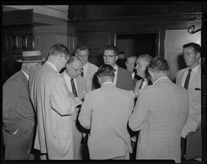 Men standing, gathered around something in the municipal court lobby