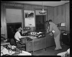 Four people in office setting, two at the desk