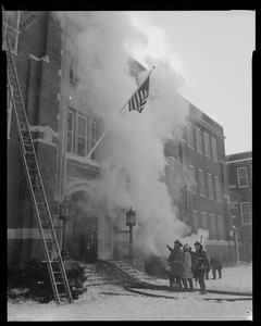 Close-up of building fire with firemen and American flag waving