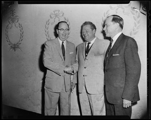 Two men shaking hands while another looks on