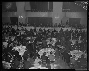 Crowd seated at tables with panel seated in background