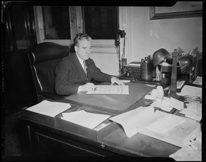 John E. Kerrigan, acting Mayor of Boston, sitting at desk signing Jerry Colonna's City of Boston award
