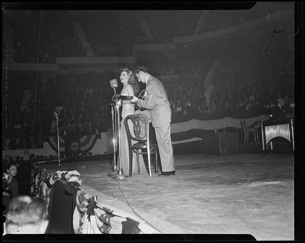 Performers on stage, a woman singing and man playing a guitar