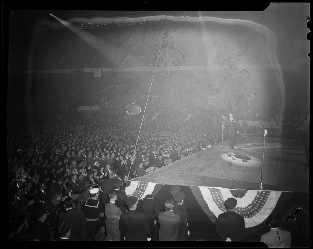 Bob Hope carrying microphone on stage with watching crowd