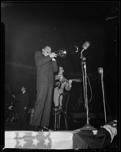 Jerry Colonna playing trombone on stage, with a guitar player