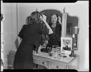 Helen Hayes primps her hair in a mirror