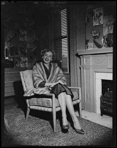 Christine Jorgenson sitting in chair, by a fireplace