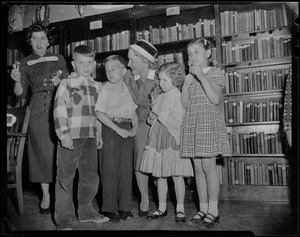 Helen Hayes and another woman with John McManus and three other children in a library at St. John's School, Quincy