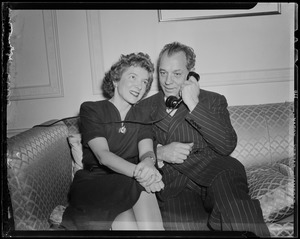 Helen Hayes posing on a couch with husband Charles MacArthur, who is on the phone