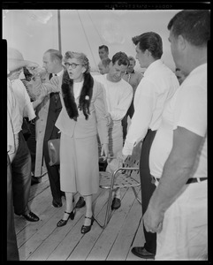 Woman, possibly a passenger, standing and speaking while men try to help her into a chair
