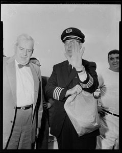 American Airlines pilot holding hand up in front of face, with two other men