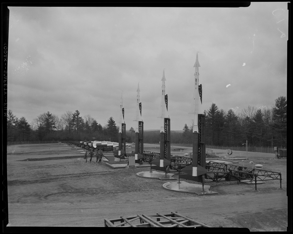 View of the Nike site, with five men running past missiles Digital