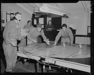 Two military men moving markers on a table with three others