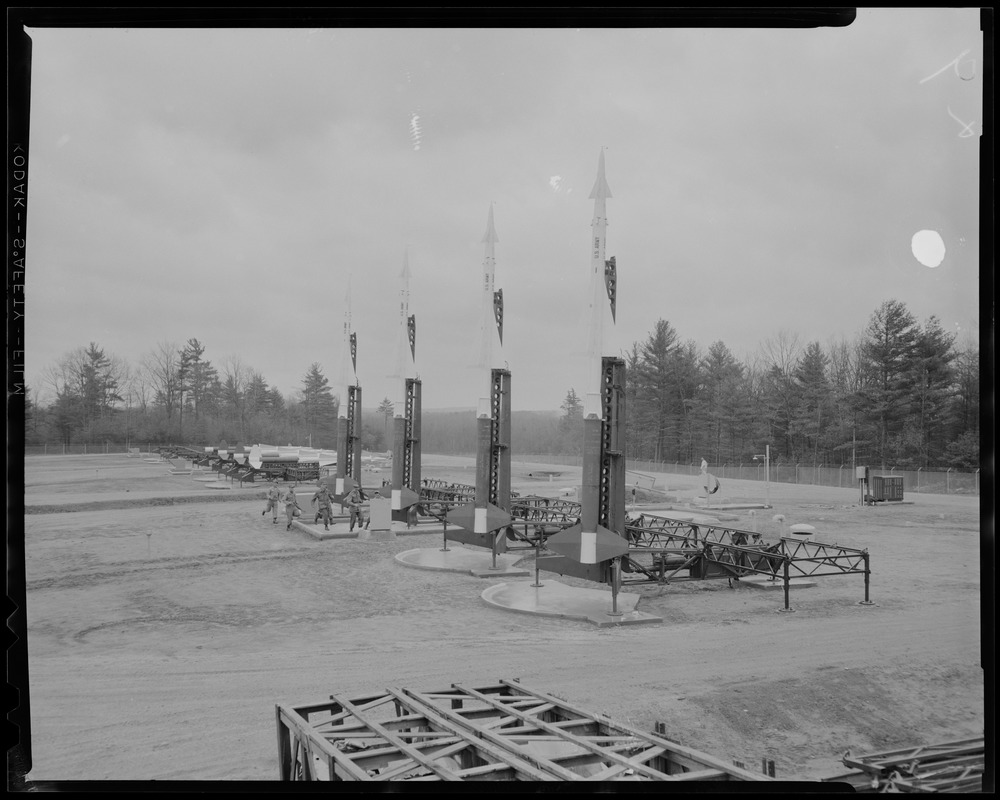 View of the Nike site, with six men running toward missiles