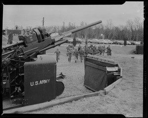 Men in military uniform running towards artillery