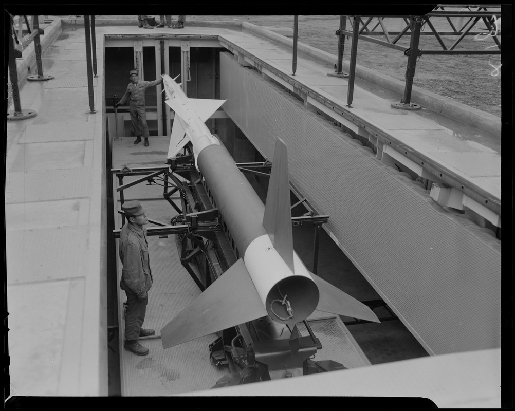 Two men in military uniform with Nike missile