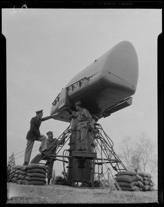 Three military men around artillery equipment