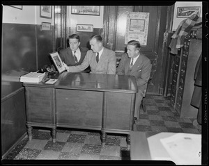 Walter Brown and two men sitting at a desk, looking at a framed image of the Boston Garden