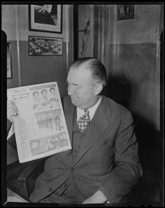 Walter Brown holding up an article about Koreans training for Boston Marathon, and Bostonians training for Korean War
