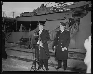 Two men speaking in front of the USS Atka