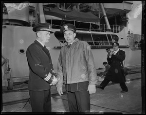 Two officers speaking in front of the USS Atka