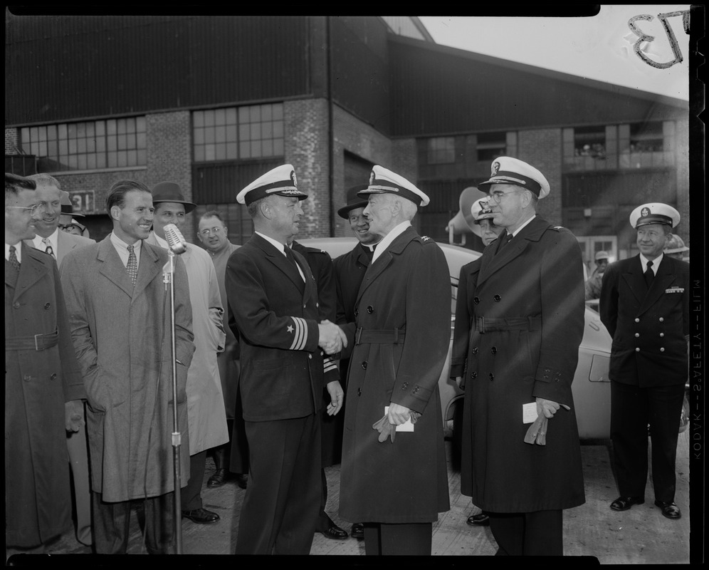 Group of commanding officers meeting on shore surrounded by people