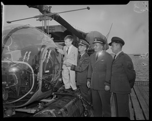 Three officers and a child looking at a helicopter on the ship