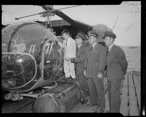 Three officers and a boy looking at a helicopter on the U.S.S. Atka