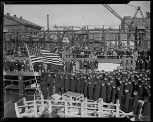 View of the crew standing at attention before the American flag onboard the U.S.S. Higbee