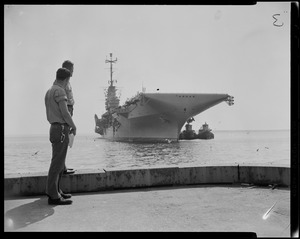 Two men standing on a platform looking at a ship
