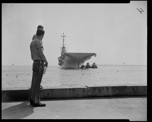 Two men standing on a platform looking at a ship