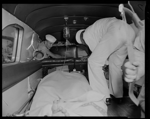 View of two men inside of an ambulance with another man laying on a stretcher