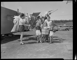 Woman and five children standing outside by a laundry line