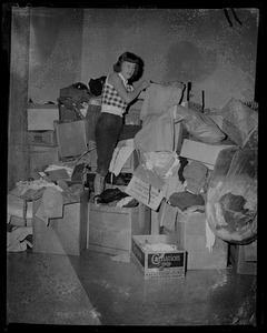 Woman holding up clothing, surrounded by boxes