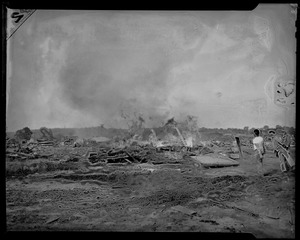 Three men standing by wreckage in field