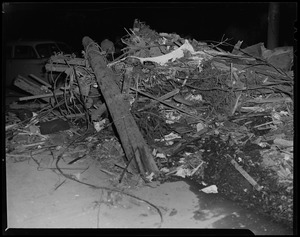 Pile of wreckage next to a vehicle, with men in the background