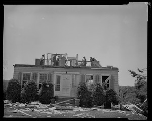 A group of five people on top of home's second floor, which is missing the walls and roof