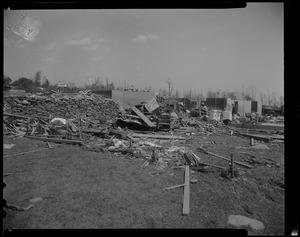 Piles of wreckage and men in the background sorting through