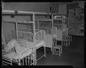 Occupied cribs and beds, with nurses in the background